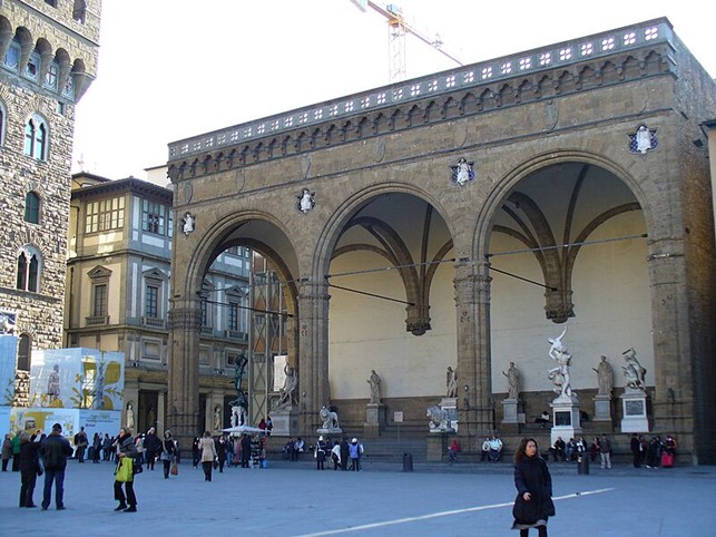 The Logia de’ Lanzi, an open air museum with invaluable statues, on the very left, in bronze, the Perseus by Benvenuto Cellini. Between the Loggia and Palazzo Vecchio the Uffizi Gallery can be seen.